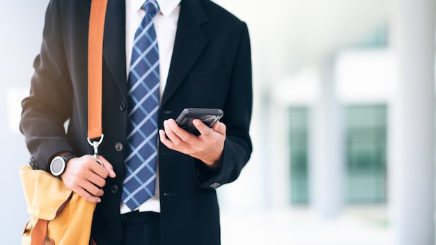 Photo jeune homme d'affaires sur smartphone marchant dans la rue à l'aide de textos app sur smartphone.