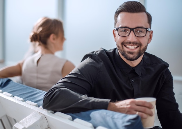 Jeune homme d'affaires avec une tasse de café assis dans un bureau moderne