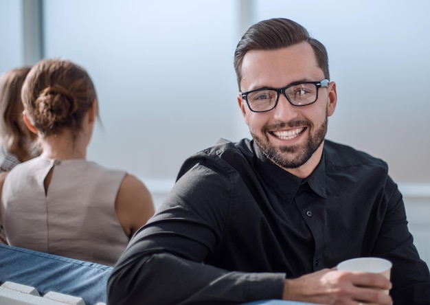 Jeune homme d'affaires avec une tasse de café assis dans un bureau moderne