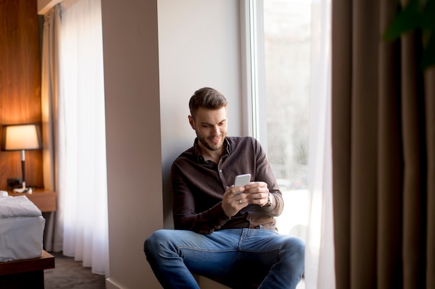 Jeune homme d&#39;affaires avec un téléphone portable par la fenêtre