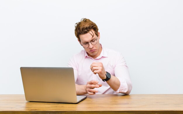 Jeune homme d'affaires à la tête rouge travaillant dans son bureau avec une horloge