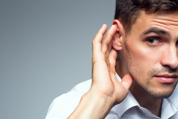 Jeune homme d'affaires tient sa main près de l'oreille Portrait en gros plan