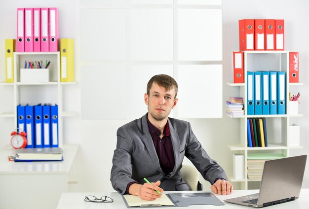 Jeune homme d'affaires travaillant dans un bureau, un gestionnaire masculin travaille sur un ordinateur portable. Homme occupé dans un lieu de travail moderne.