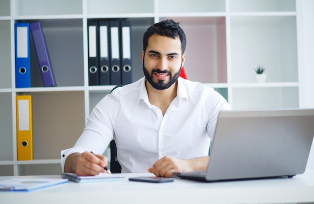 Jeune homme d'affaires travaillant sur ordinateur au bureau