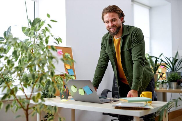 Jeune homme d'affaires travaillant sur ordinateur portable au bureau. homme affaires, debout, bureau