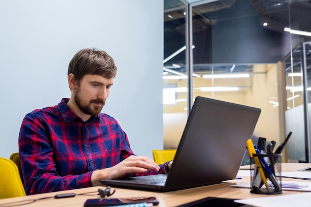 Jeune homme d'affaires travaillant sur ordinateur portable dans un bureau de coworking