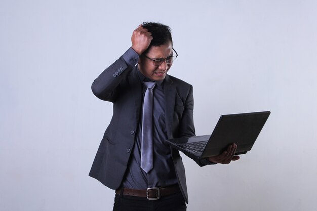 Jeune homme d'affaires travaillant sur ordinateur portable et semble frustré