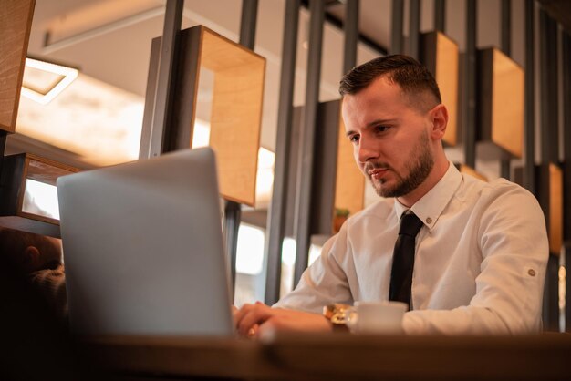 Photo un jeune homme d'affaires travaille sur un ordinateur portable dans un café-restaurant.