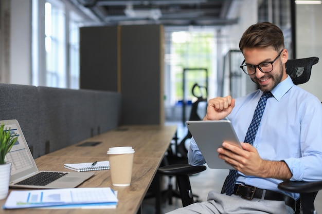 Jeune homme d'affaires utilisant sa tablette au bureau.