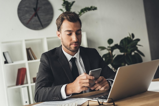 jeune homme d'affaires utilisant un smartphone sur le lieu de travail