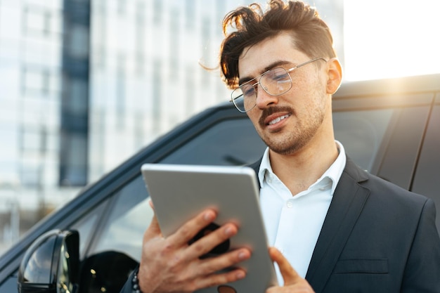 Jeune homme d'affaires utilisant une tablette numérique tout en se tenant à l'extérieur