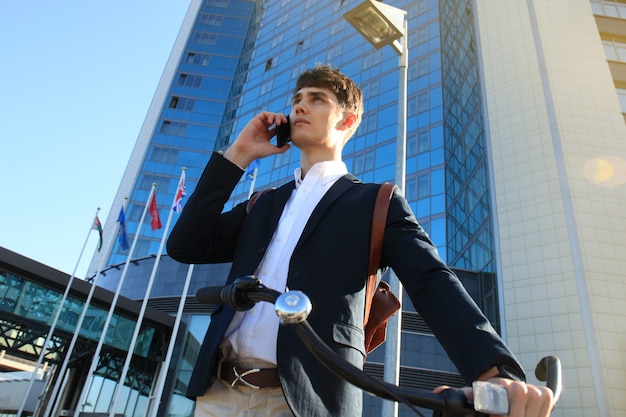 Jeune homme d'affaires avec vélo et smartphone dans la rue de la ville.