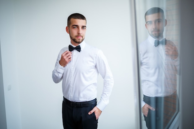 Jeune homme d'affaires vêtu d'une chemise blanche avec une barbe courte porte un nœud papillon noir