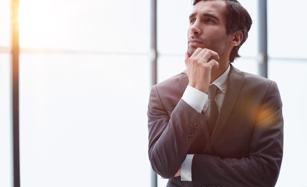 Jeune homme d'affaires en vue de profil avec la main sur le menton au bureau