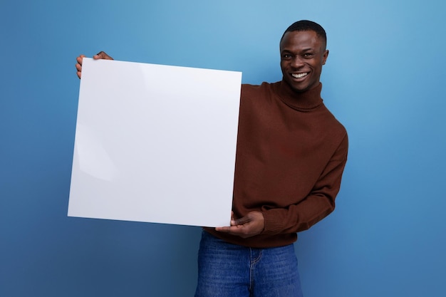 Jeune homme africain annonce un produit avec affichage sur une feuille blanche