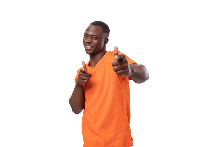 Un jeune homme africain confiant, vêtu d'un t-shirt orange, montre la classe et aime avec sa main