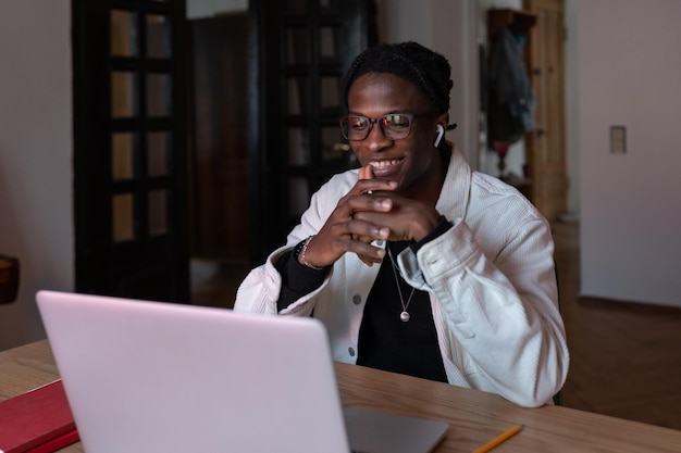 Jeune homme africain heureux souriant travaillant à distance dans des lunettes regardant un écran d'ordinateur portable lisant un e-mail