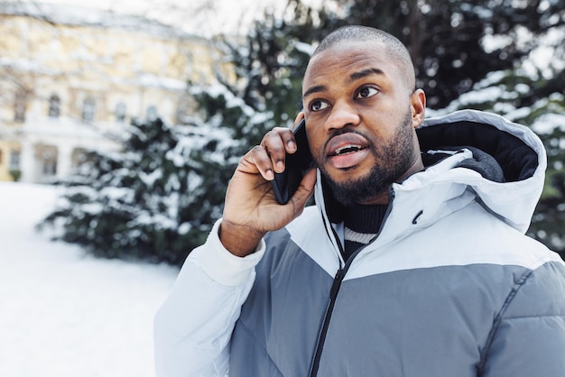 Jeune homme africain homme parlant au téléphone choqué hiver extérieur