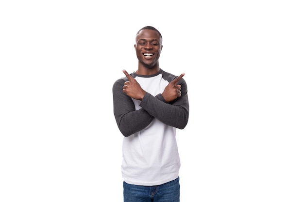 Un jeune homme africain intelligent avec une coupe de cheveux courte vêtu d'un sweat-shirt et de jeans veut