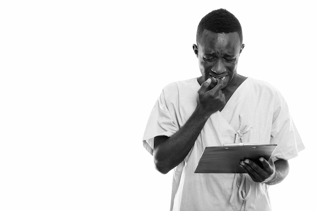 Jeune homme africain noir patient lisant sur le presse-papiers tout en regardant inquiet et se mordant l'ongle