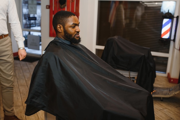 Jeune homme africain obtient une nouvelle coupe de cheveux dans un salon de coiffure