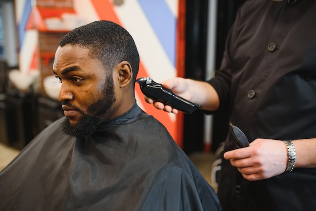 Jeune homme africain obtient une nouvelle coupe de cheveux dans un salon de coiffure