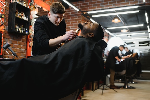 Jeune homme africain obtient une nouvelle coupe de cheveux dans un salon de coiffure