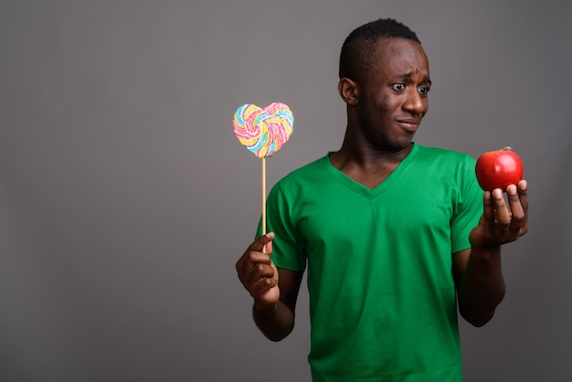 Jeune homme africain portant une chemise verte sur un mur gris