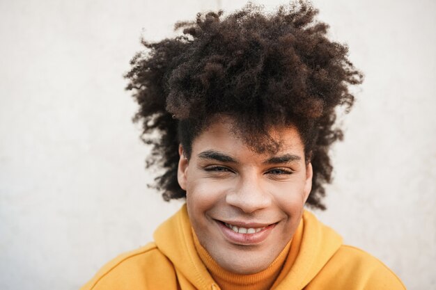 Jeune homme africain souriant à la caméra en plein air dans la ville - Focus on face