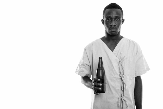 Jeune homme africain en tant que patient hospitalisé isolé contre un mur blanc en noir et blanc