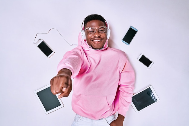 Jeune homme afro-américain à l'aide de gadgets d'appareils isolés sur fond de studio blanc