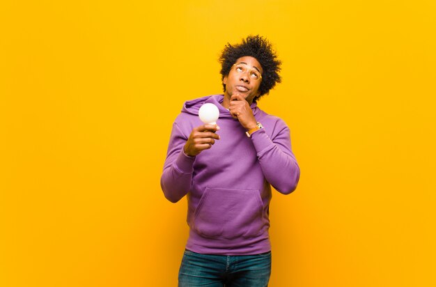 Jeune homme afro-américain avec une ampoule contre dos orange