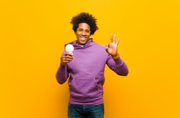 Jeune homme afro-américain avec une ampoule contre orange