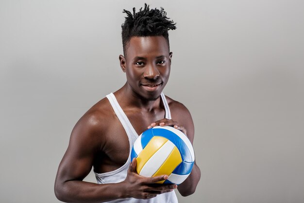 Jeune homme afro-américain athlétique avec ballon de volley-ball en regardant la caméra