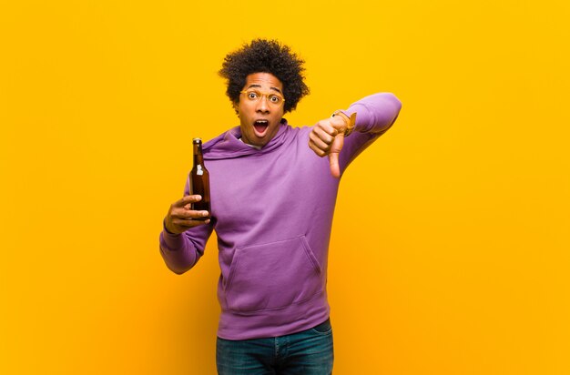 Jeune homme afro-américain avec une bière contre orange