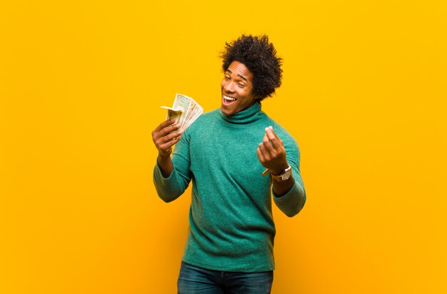 Jeune homme afro-américain avec billets d'un dollar contre dos orange