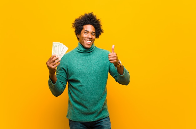 Jeune homme afro-américain avec billets d'un dollar contre le dos orange