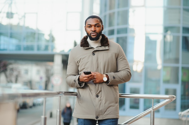 Jeune homme afro-américain dans des vêtements élégants posant à l'extérieur