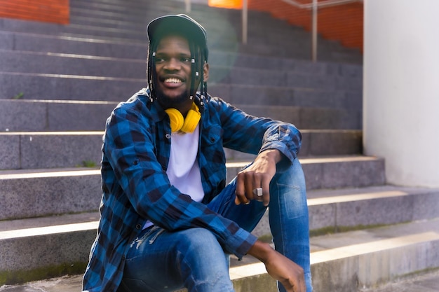 Jeune homme afro-américain dans la ville portrait d'un jeune homme alternatif en chemise à carreaux bleu avec casquette