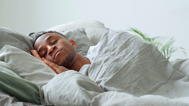 Jeune homme afro-américain dormir dans son lit à la maison