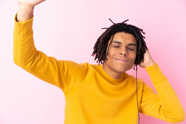 Jeune homme afro-américain, écouter de la musique sur le mur rose