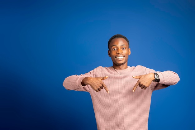 Un jeune homme afro-américain étonné et joyeux en sweat-shirt rose regarde la caméra.