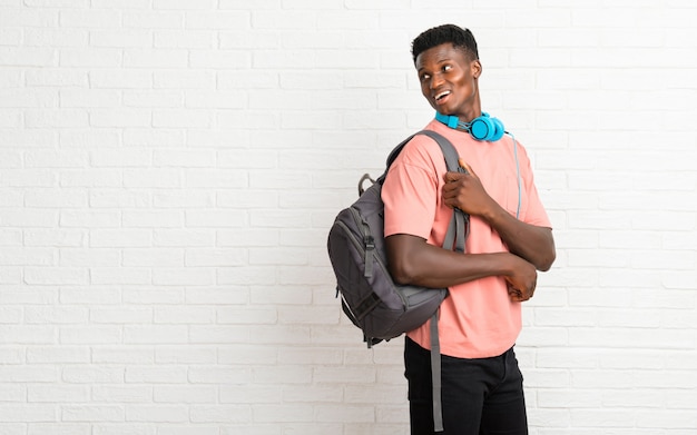 Jeune homme afro américain étudiant en position latérale en regardant par-dessus l&#39;épaule avec un sourire