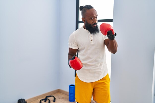 Jeune homme afro-américain avec expression sérieuse boxe au centre sportif