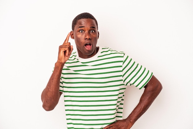 Jeune homme afro-américain isolé sur fond blanc ayant une idée, concept d'inspiration.