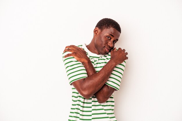 Jeune homme afro-américain isolé sur fond blanc câlins, souriant insouciant et heureux.