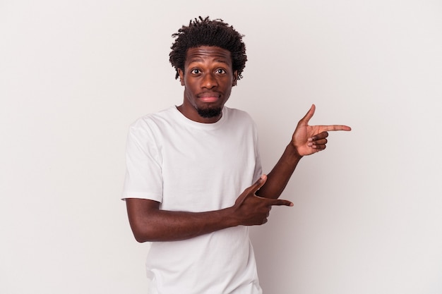 Jeune homme afro-américain isolé sur fond blanc choqué pointant avec l'index vers un espace de copie.