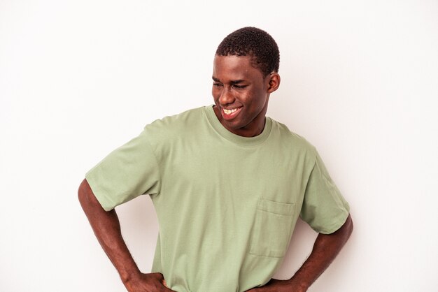 Jeune homme afro-américain isolé sur fond blanc confiant en gardant les mains sur les hanches.