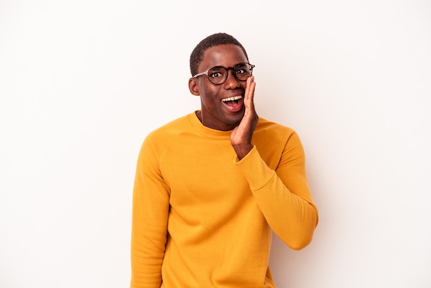 Jeune homme afro-américain isolé sur fond blanc crie fort, garde les yeux ouverts et les mains tendues.