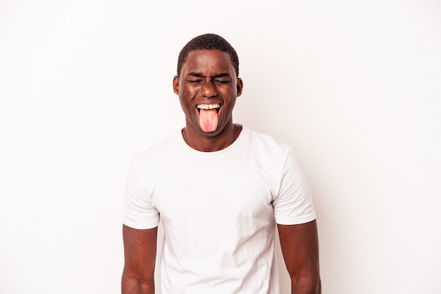 Jeune homme afro-américain isolé sur fond blanc drôle et sympathique qui sort la langue.